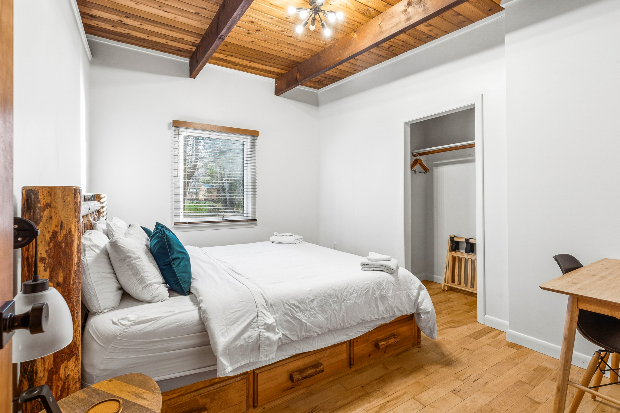 King bedroom with Sputnik chandelier and exposed wood beams