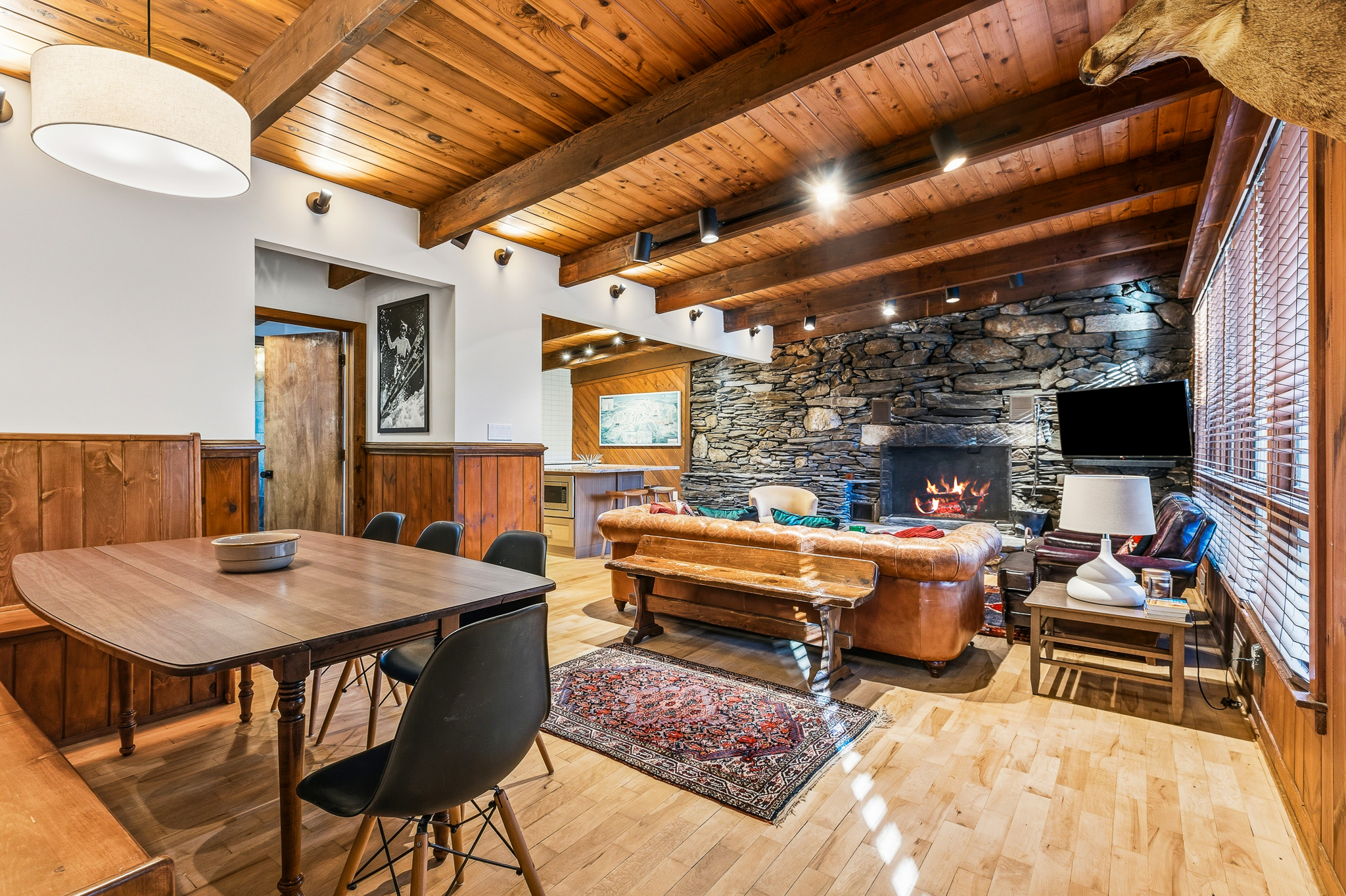 Open-plan living and dining with stone fireplace and beamed ceilings