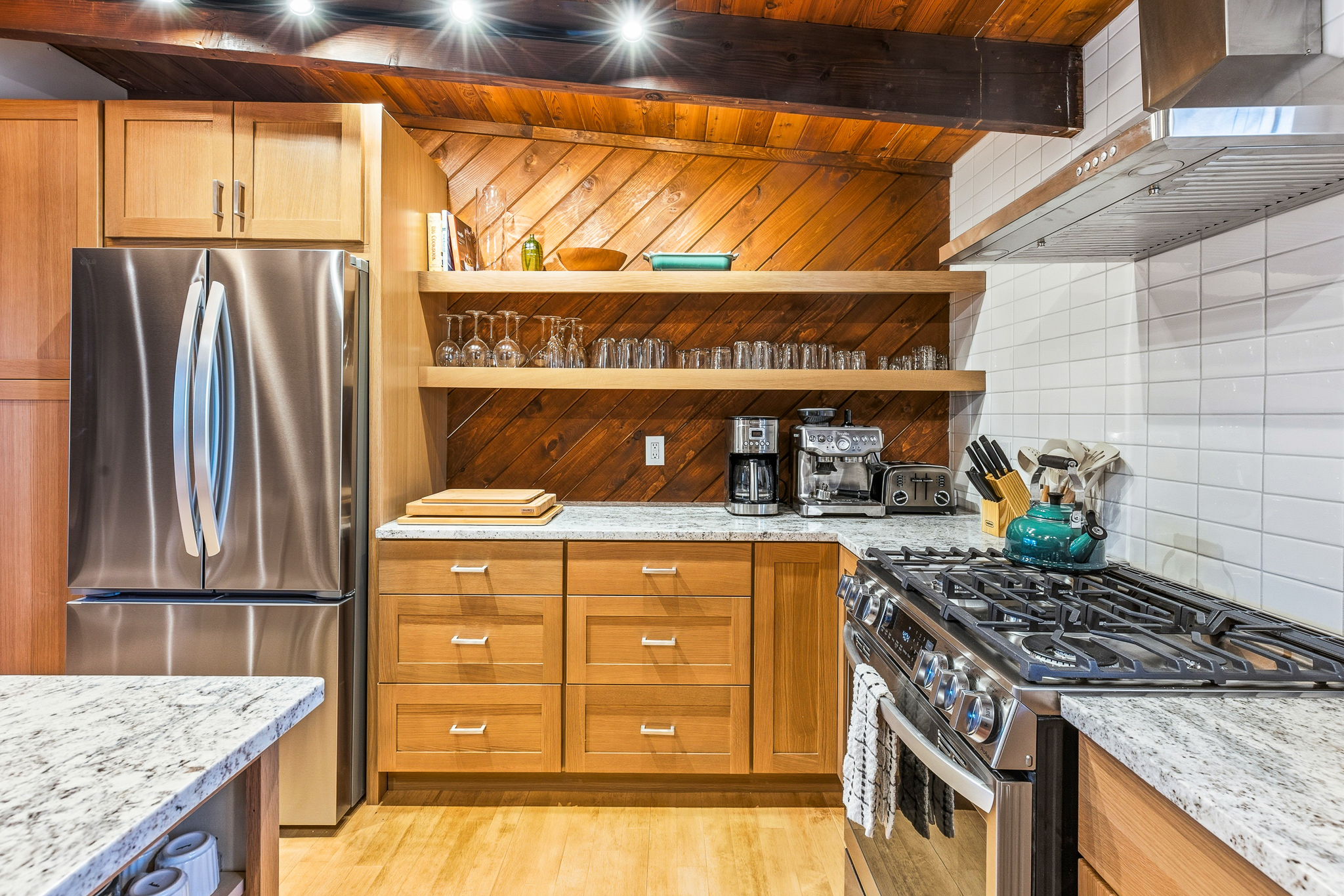 Chef's kitchen with marble counters, open shelving, and wood beam ceiling